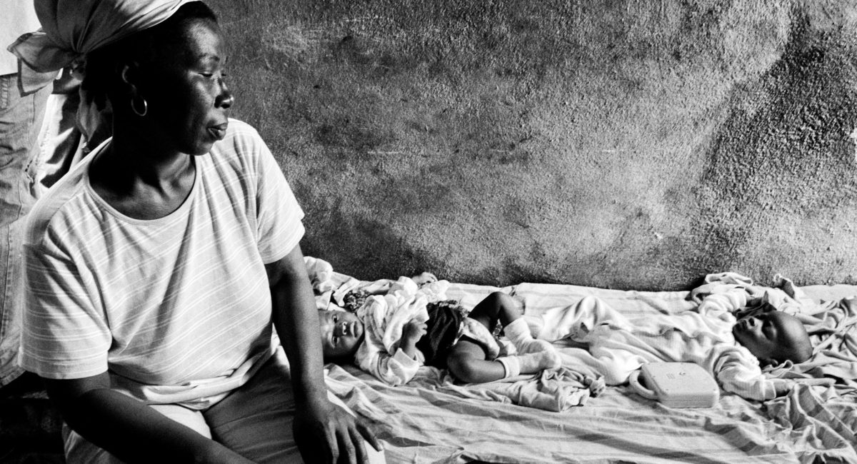 A woman sits on a bed next to her 8 months old twins. Deliver twins in Wharf Jeremie could be a serious problem. Many times a mother has no food enough to feed both sons. Waf Jeremie is one of the poorest districts of Port au Prince, a shantytown where about 150.000 people live in miserable conditions and where gangs, drug and arms dealers are free to increase their business. This is one of the areas forbidden by UN because of its dangerousness. Waf Jeremie is built on a garbage dump among the sea and a little smelly, dark river. This is a high risk area for deseases. After hurricane Tomas great part of it was flooded and Waf Jeremie is one of the first Port au Prince areas where cholera appeared.