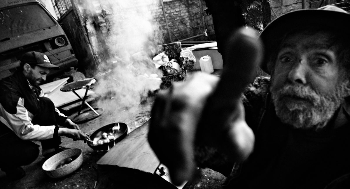 Rome, Italy.
Gypsies cooking on the floor inside an abandoned factory where they built their shacks.
 At the entrance, on the wall, it's written : welcome, bienveue!