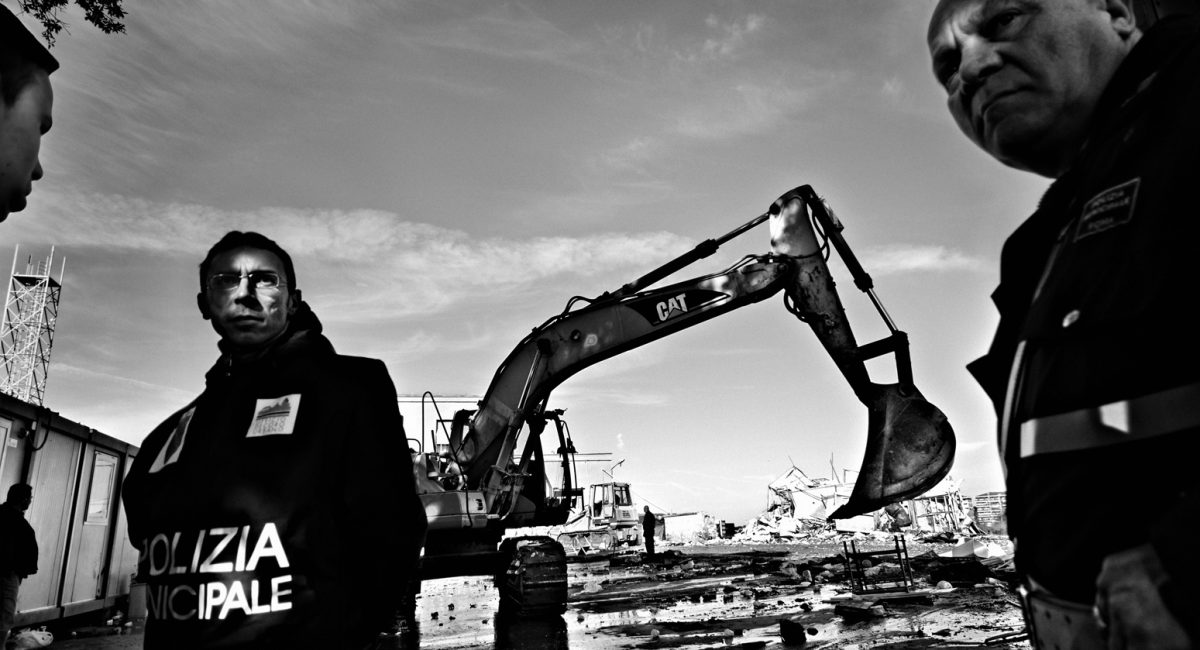 Rome, Italy.
Police agents during romanian roma pull out from Villa Troili camp. The ditching machine is destroying containers where roma were living. Once gypsies have been pulled out, they don't have a place to go. Some of them found a place under motorway bridges, others along the Tevere river or in the woodlands.